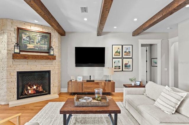 living room with beam ceiling, a fireplace, and light hardwood / wood-style floors