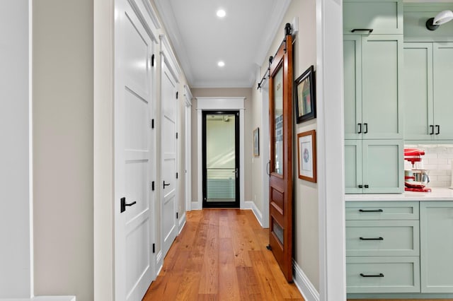 corridor featuring a barn door, crown molding, and light hardwood / wood-style flooring