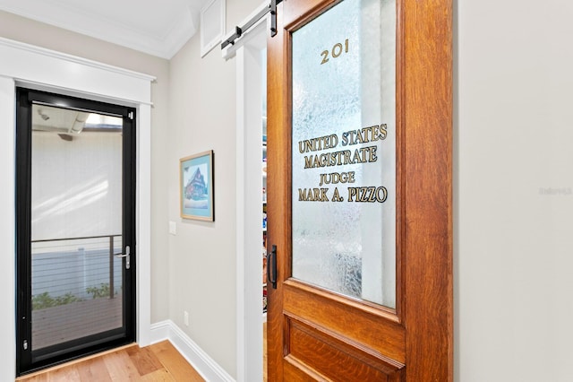 doorway to outside featuring crown molding, a barn door, and light hardwood / wood-style floors