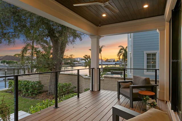 deck at dusk with ceiling fan and a water view