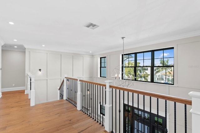 hall featuring ornamental molding, light hardwood / wood-style floors, and a chandelier