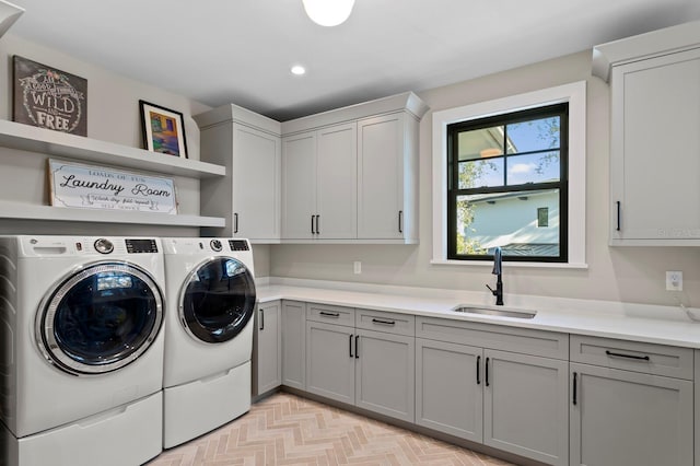 laundry area with light parquet flooring, washing machine and dryer, sink, and cabinets