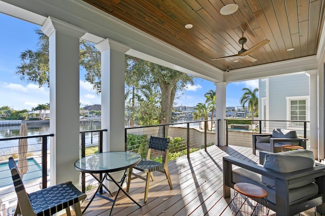 deck featuring ceiling fan and a water view