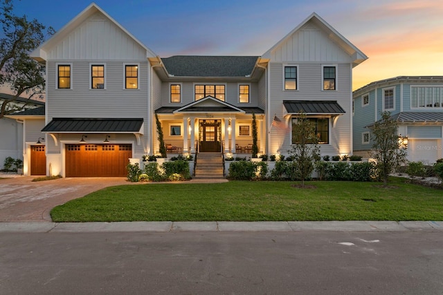 modern farmhouse style home featuring a garage, a porch, and a lawn