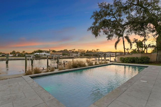 pool at dusk featuring a water view