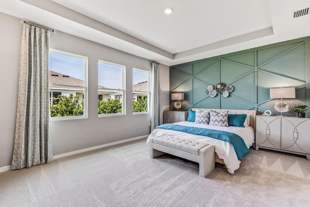 bedroom with a raised ceiling and light carpet