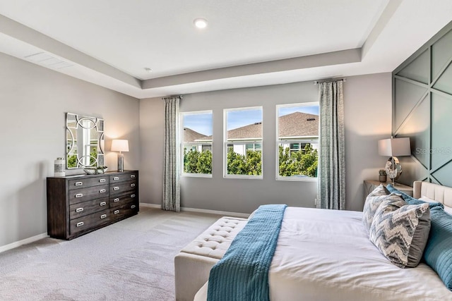 bedroom with a tray ceiling and light colored carpet