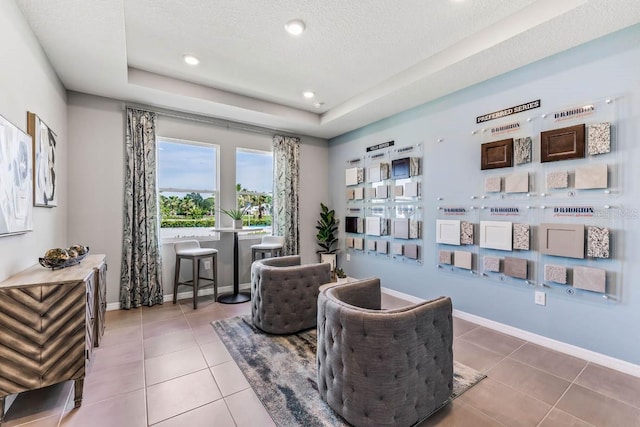 living area with a textured ceiling, a tray ceiling, and tile patterned floors