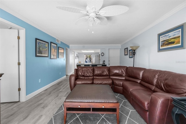 living room featuring hardwood / wood-style flooring, ceiling fan, and crown molding