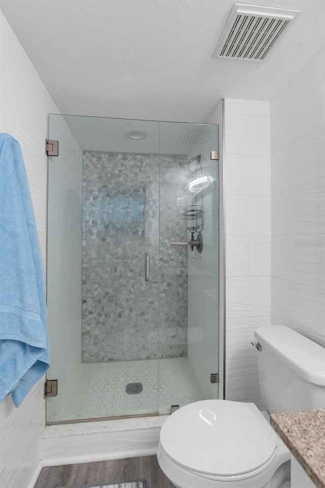 bathroom featuring toilet, vanity, a shower with door, and hardwood / wood-style flooring