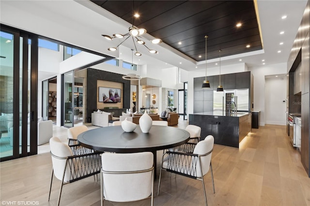 dining room featuring a high ceiling, a tray ceiling, light hardwood / wood-style floors, and sink