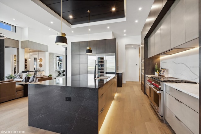 kitchen featuring decorative light fixtures, range with two ovens, a spacious island, and dark stone countertops