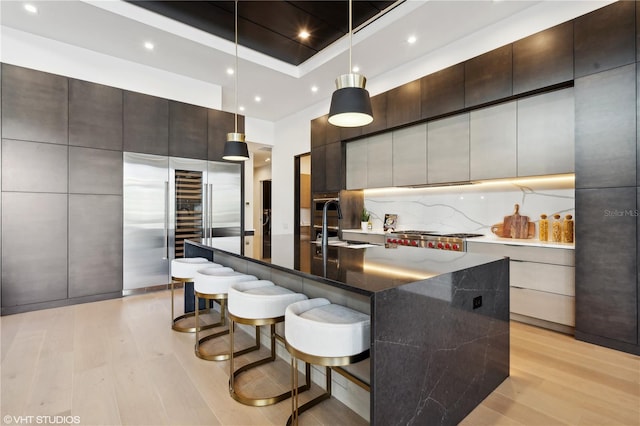 kitchen with a kitchen breakfast bar, a large island, light hardwood / wood-style flooring, and decorative light fixtures