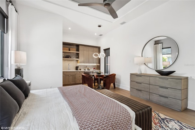 bedroom with connected bathroom, light wood-type flooring, ceiling fan, and sink