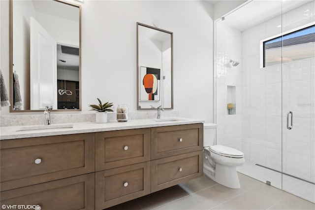 bathroom with tile patterned flooring, vanity, a shower with shower door, and toilet