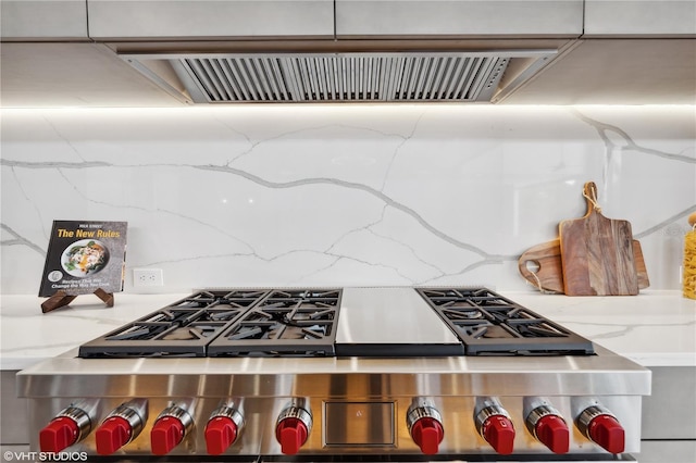 kitchen with ventilation hood, light stone countertops, and stainless steel stove