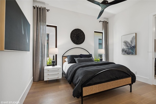 bedroom featuring multiple windows, hardwood / wood-style flooring, and ceiling fan