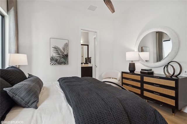 bedroom with multiple windows, ensuite bathroom, and hardwood / wood-style flooring