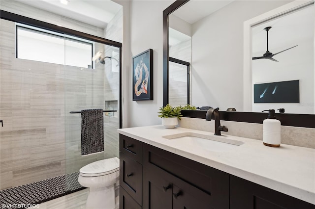 bathroom featuring vanity, toilet, ceiling fan, and a shower with shower door