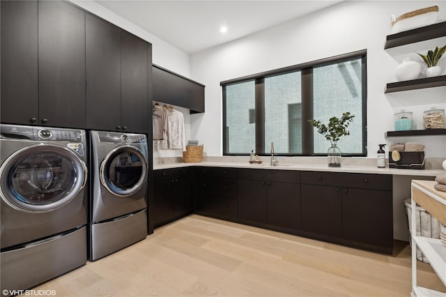 washroom featuring cabinets, independent washer and dryer, light hardwood / wood-style flooring, and sink