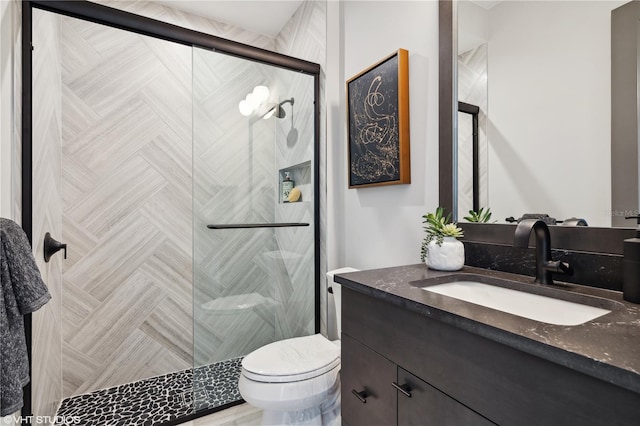 bathroom featuring vanity, toilet, and a shower with shower door