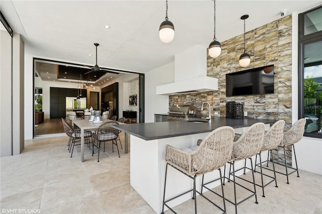 kitchen featuring a kitchen breakfast bar, plenty of natural light, hanging light fixtures, and custom exhaust hood