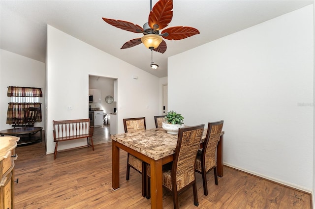 dining room with ceiling fan, wood-type flooring, and vaulted ceiling