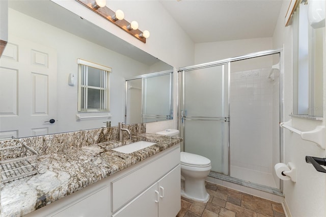 bathroom featuring vanity, toilet, and a shower with door