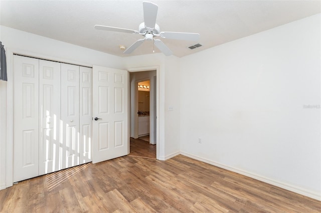 unfurnished bedroom featuring a textured ceiling, a closet, light hardwood / wood-style floors, and ceiling fan