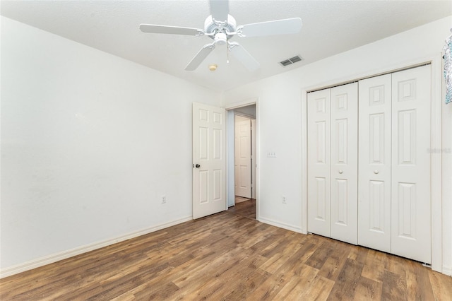 unfurnished bedroom featuring a closet, ceiling fan, dark hardwood / wood-style flooring, and a textured ceiling