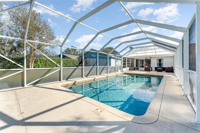 view of pool with glass enclosure, ceiling fan, a patio, and an outdoor hangout area