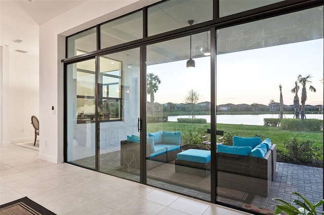 doorway with a water view, a wall of windows, a healthy amount of sunlight, and light tile patterned flooring