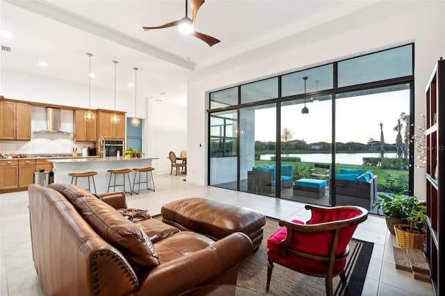 living room with light tile patterned floors, a water view, and ceiling fan