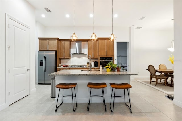 kitchen with wall chimney exhaust hood, stainless steel appliances, sink, hanging light fixtures, and a breakfast bar area