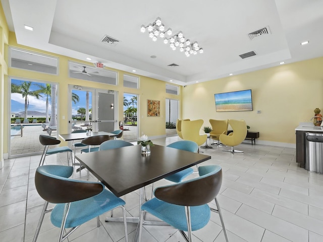 dining space featuring a tray ceiling, ceiling fan, french doors, and light tile patterned floors