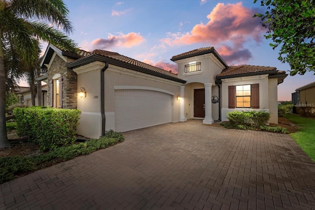23503 Waverly Cir, Venice, FL 34293 - mediterranean / spanish-style home featuring a garage, stucco siding, decorative driveway, a tiled roof, and stone siding
