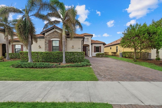 23503 Waverly Cir, Venice, FL 34293 - mediterranean / spanish-style house with stucco siding, a tiled roof, a front lawn, decorative driveway, and stone siding