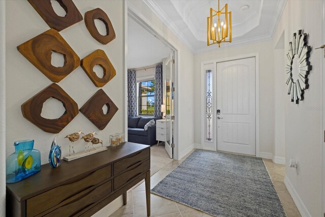 23503 Waverly Cir, Venice, FL 34293 - entryway with a chandelier, crown molding, light tile patterned flooring, a tray ceiling, and baseboards