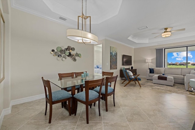 tiled dining space featuring a tray ceiling, crown molding, and ceiling fan