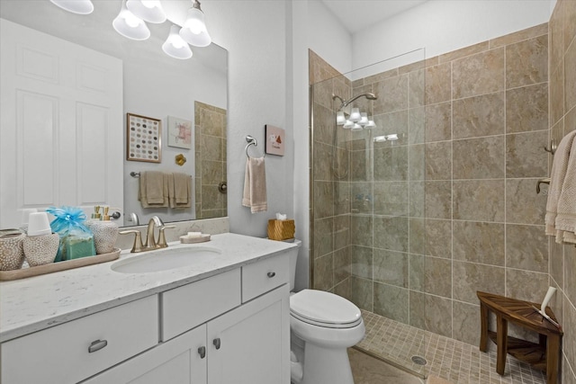 bathroom with a tile shower, vanity, toilet, and a notable chandelier