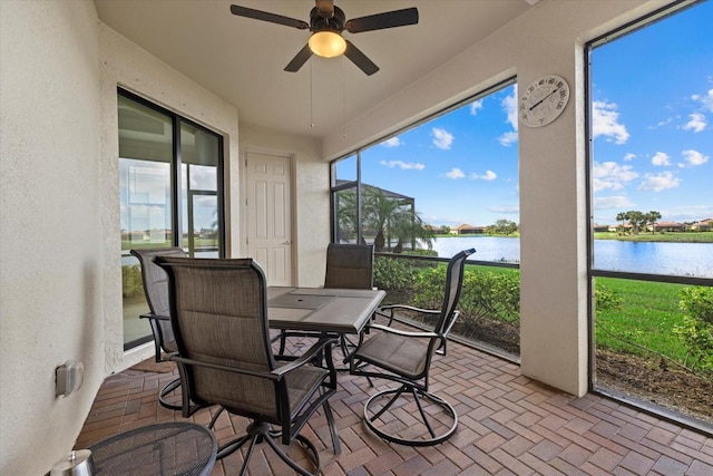 sunroom / solarium with a wealth of natural light, ceiling fan, and a water view