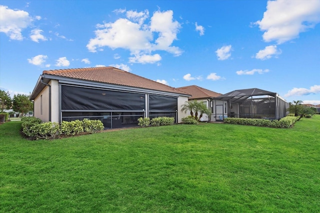 back of house with glass enclosure and a lawn