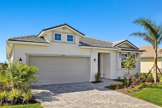 12241 Meditation Trl, Venice, FL 34293 - view of front of property featuring stucco siding, an attached garage, decorative driveway, and a tiled roof