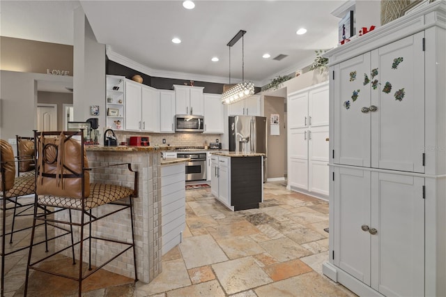 kitchen featuring kitchen peninsula, a breakfast bar, stainless steel appliances, decorative light fixtures, and white cabinets