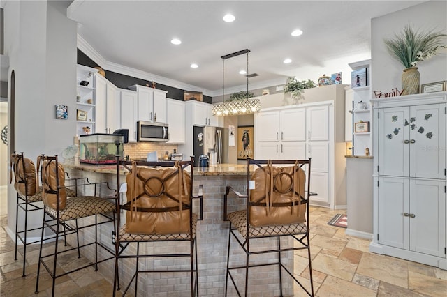 kitchen featuring decorative light fixtures, ornamental molding, a breakfast bar area, and appliances with stainless steel finishes