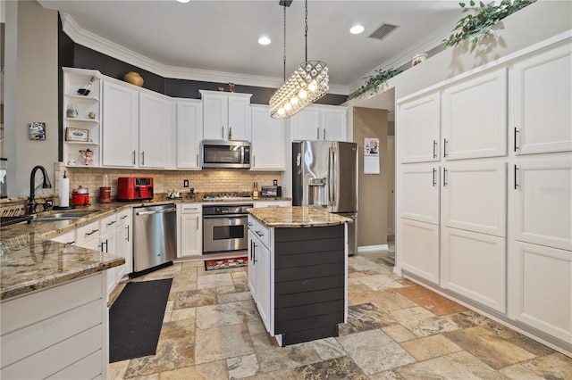 kitchen featuring crown molding, decorative backsplash, appliances with stainless steel finishes, decorative light fixtures, and light stone counters