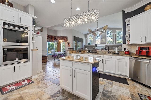 kitchen with white cabinets, appliances with stainless steel finishes, decorative light fixtures, and a healthy amount of sunlight