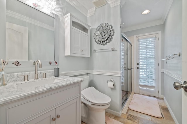 bathroom with toilet, vanity, an enclosed shower, and ornamental molding