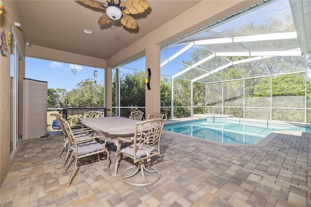 view of pool featuring glass enclosure, ceiling fan, and a patio