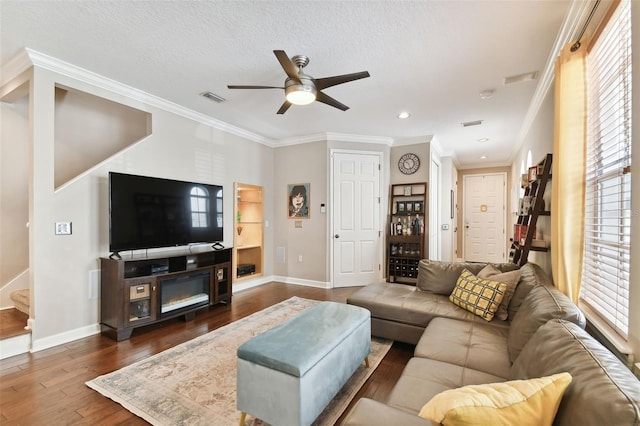 living room featuring ceiling fan, ornamental molding, dark hardwood / wood-style floors, and a textured ceiling